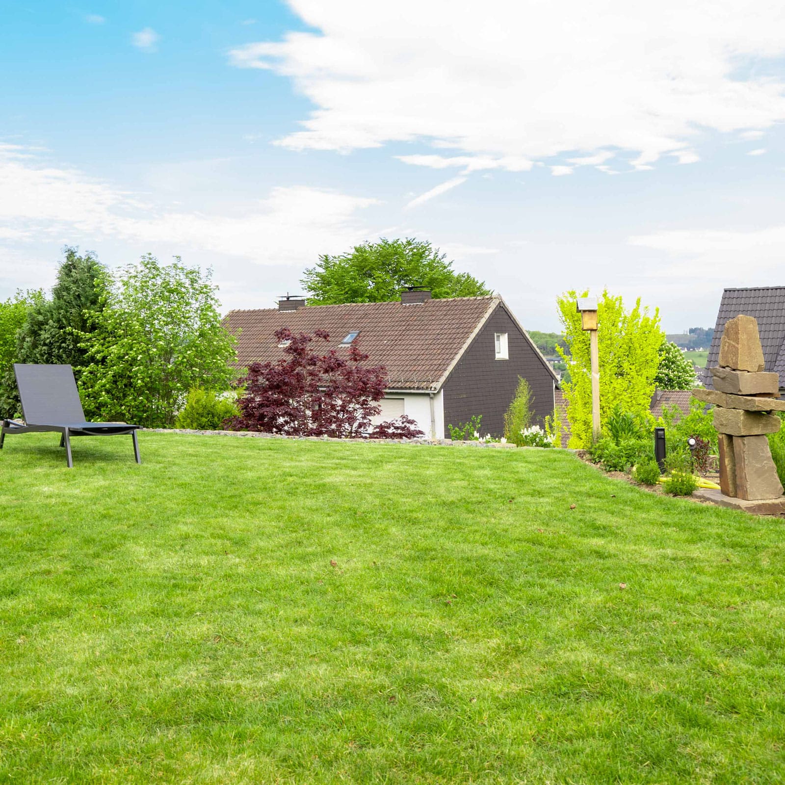 Ein Garten mit grüner Wiese und einem Liegestuhl